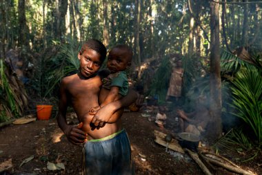 Baka kabilesinden pigme çocuk küçük kardeşini yağmur ormanları köyünde tutuyor. Geleneksel Afrika ormanlarında sevgi ve güven anı
