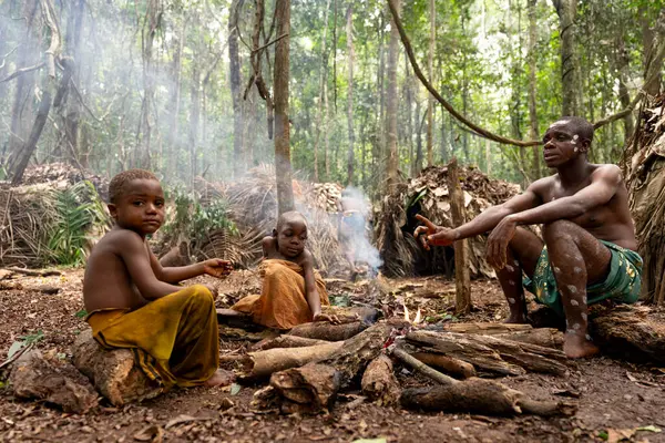 Afrika yağmur ormanlarının derinliklerindeki Baka köyünde ateşin altında pigme adam ve çocuklar günlük yaşam anlarını gösteriyor.