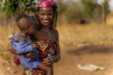 Gülümseyen anne çocuğunu kucağında tutuyor, neşe, sevgi ve nesiller boyu Afrika 'nın bir köyündeki bağları yakalıyor..