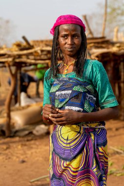 Genç Mbororo annesi bebeğini renkli kumaşa sarmış, gücü, güzelliği ve Afrikalı anneliğin derin geleneklerini yansıtan bir portre..