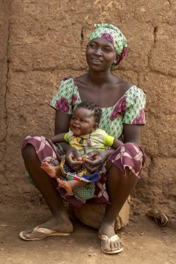 Gülümseyen bebeğiyle Dowayo denen kadın, Kamerun 'daki günlük köy yaşamında sevgi, neşe ve aile bağlarının gücünü gösteriyor..