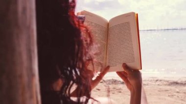 Sahilde kitap okuyan bir kadın.