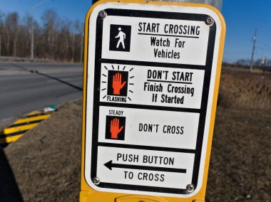 Net talimatları olan yaya geçidi tabelası. Semboller ve metin rehberleri yürümenin güvenli olduğu, geçişi ne zaman yapacakları ve bir sonraki sinyali ne zaman bekleyecekleri konusunda yayalara rehberlik ederler..