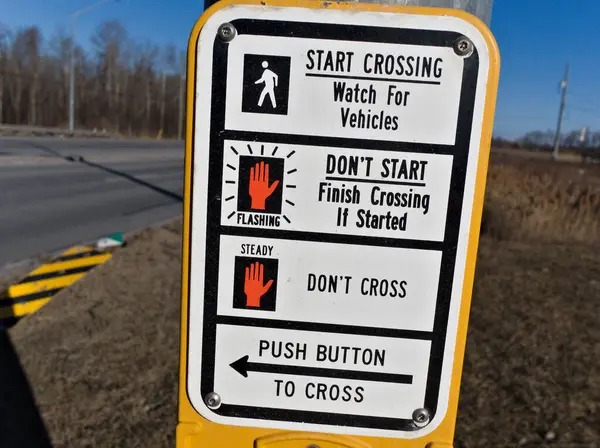 Net talimatları olan yaya geçidi tabelası. Semboller ve metin rehberleri yürümenin güvenli olduğu, geçişi ne zaman yapacakları ve bir sonraki sinyali ne zaman bekleyecekleri konusunda yayalara rehberlik ederler..