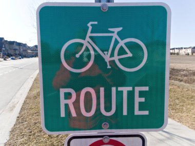 Açık bir gökyüzüne karşı belirgin bir şekilde gösterilen bisiklet yolu tabelası, çevre dostu seyahat ve açık hava keyfine işaret ediyor.