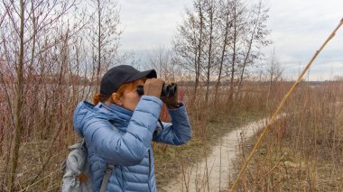 Maceraperest kadın kuş yaşamını dürbünle gözlemlerken tenha ve mevsimsel olarak çorak bir araziyi keşfediyor..