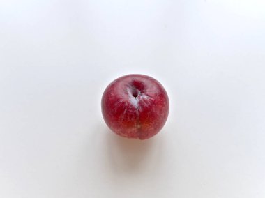 Beyaz arka planda kırmızı bir elma oturuyor. Elma hafif çürük ve içinde küçük bir delik var. Elmanın basit olduğu gibi, basitlik ve doğal güzellik kavramı.