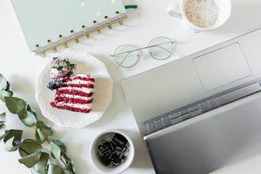 Kırmızı kadife pastalı kahvaltı kompozisyonu ve beyaz arka planda bir fincan süt ve kahve. Düz yatış, üst görünüm.