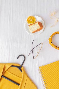 Üst görünüm ofis masası çerçeve dizüstü bilgisayar, turuncu kek, hırka, gözlük ve planlayıcı beyaz arka planda. 