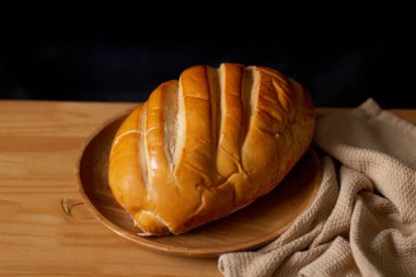 Tahta masadaki izole edilmiş beyaz ekmek. Karanlık kompozisyon. Fırın kavramı. 