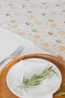 Renkli masa örtüsünde taze sapla süslenmiş beyaz tabak.