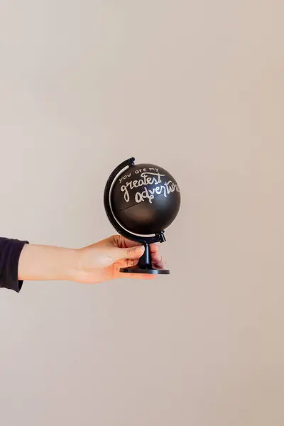 Female hand holding a black globe written: 