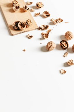 Sonbahar kompozisyonu, ceviz ve beyaz arka plandaki tahta üzerinde boş kabuklar..