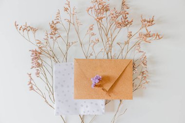 Düğün davetiyesi zarfı, beyaz arka planda leylak çiçekleri. Düz yatış, üst görünüm. 