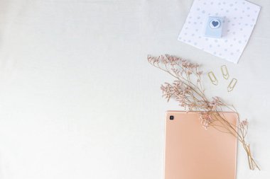 Saf altın tablet yatıyordu ve rahat bir yer tasarlıyordu. Üst kattaki ofis masası çalışma alanı kurumuş çiçek dalları ve kırtasiye malzemeleriyle dekore edilmiş.. 