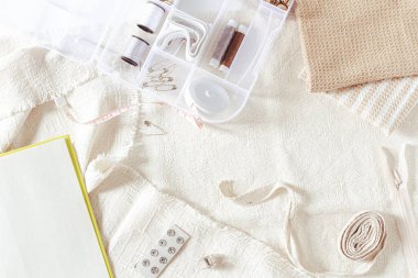 Dikiş takımı, boş sayfalar dolusu kitap ve kumaş çarşaflar. Düz yerde, üst tarafta. Hobi, eğlence konsepti. 