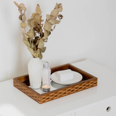 Okaliptüs vazosu, sabun, cilt bakım ürünleri ve ayna tepsisindeki mum. Estetik minimalist kompozisyon.