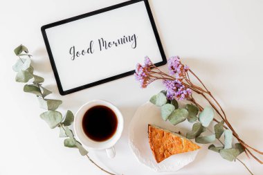 Tablet, çiçek çerçevesi ve beyaz arka planda kahvaltı kompozisyonu üzerinde 