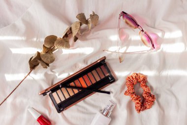 Kadın stili aksesuarlar: beyaz arka planda bardaklar, saç bandı, kır çiçekleri ve kozmetik ürünleri. 