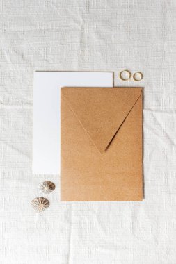 Tahta masanın üzerinde alyanslar olan el işi zarf.