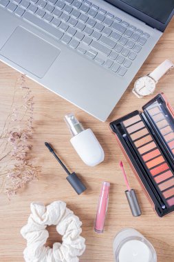 Güzellik blogu moda konsepti. Kadın stili aksesuarlar: dizüstü bilgisayar, saç tokası, kır çiçekleri ve ahşap arka planda kozmetik ürünleri. Düz yatış, üst görünüm moda kadınsı arkaplan. 