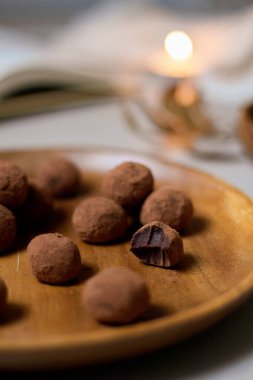 Lezzetli tatlı konsepti. Tahta tabakta kakao tozuyla kaplı çikolatalı trüf mantarlarının yakın görüntüsü.. 