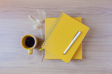 Bir fincan kahve, planlamacı, kalem, ahşap masada yabani çiçekler olan kadın ofis masası çalışma alanı. Düz yerde, üst tarafta. Yaşam tarzı blogu, sosyal medya kompozisyonu.