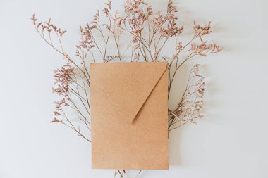 Düğün davetiyesi zarfı, beyaz arka planda leylak çiçekleri. Düz yatış, üst görünüm. 