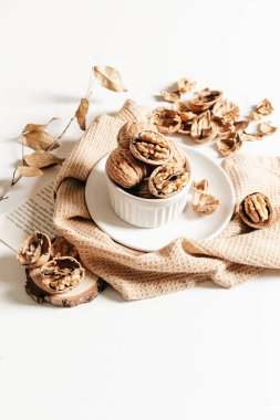 Beyaz tabakta ceviz ve beyaz arka planda el işi kağıtların rahat sonbahar kompozisyonu.