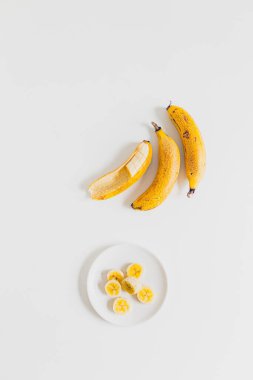 Beyaz tabakta dilimlenmiş olgun muz.