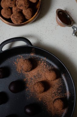Siyah tavada kakao tozuyla kaplı ev yapımı çikolatalı trüf mantarları. Gri arka plan. Lezzetli tatlı konsepti.