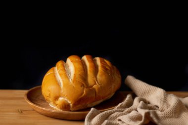 Tahta masadaki izole edilmiş beyaz ekmek. Karanlık kompozisyon. Fırın kavramı. 