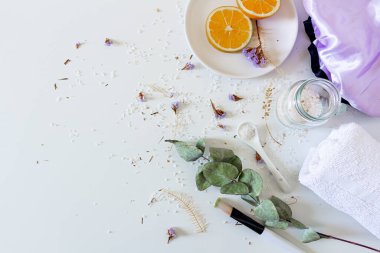 Beyaz arka planda banyo tuzu ve portakal dilimleriyle bej kaplıca kompozisyonu. Düz yerde, üst tarafta. Kadın güzellik tedavi rutin konsepti.