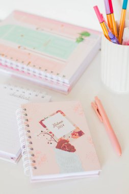 Beyaz bardakta renkli kalemli not defterleri grubu