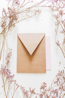 Düğün davetiyesi zarfı, beyaz arka planda leylak çiçekleri. Düz yatış, üst görünüm. 
