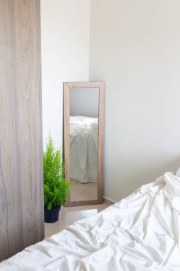 Aynadaki yatak yansıması gardıroba ve yeşil çiçeğe yakın duvara dayanıyor. Modern klasik tasarım. Evin içi rahattır.. 