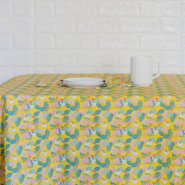 Renkli masa örtüsünde beyaz kupa olan iki seramik tabak.