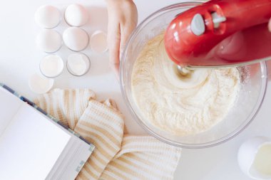 Mutfak eşyaları, beyaz arka planda pasta hazırlama konsepti. Yumurtalarla, mutfak örtüsüyle, mikserle, yemek tarifleriyle.. 