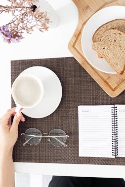 Kahvaltı sırasında kahve içen genç bir kadın.