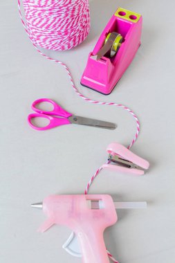 Eser gereksinimleri. Pembe tel, makas, zımba, koli bandı tutacağı ve beyaz arka planda sıcak tutkal tabancası. Kendin yap konsept.. 