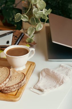 Çalışma alanı bir fincan kahve ve süt, ekmek kırtasiyesi ve mobil beyaz masa. Kafe kavramı. 