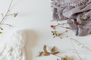 Beyaz arka planda kadın kış aksesuarları. Ilık beyaz örgü şapka ve gri eşarp. Düz yatış, üst görünüm.