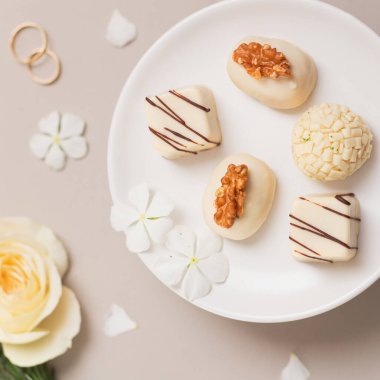 Beyaz tabakta gurme şekerler. Gri arkaplanda bahar kompozisyonu. Düğün resepsiyonu. 