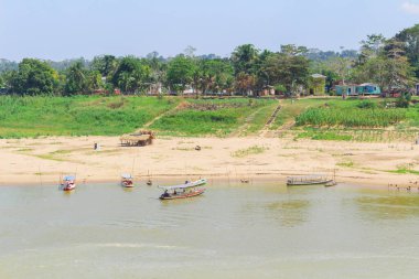 Amazon Mahallesi Peyzajı. Ahşap evler, kanolar, nehir ve palmiye ağaçları..