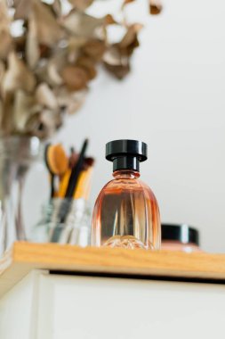 Arka planda parfüm, makyaj fırçası ve okaliptüs dallarıyla estetik minimalist güzellik kompozisyonu