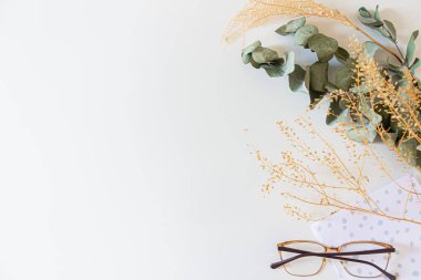 Kurumuş çiçekli bahar kompozisyonu, beyaz arka planda bardaklar ve kart.