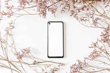 Beyaz arkaplanda cep telefonu bulunan leylak çiçeklerinden yapılmış yuvarlak çerçevenin üst görünümü 
