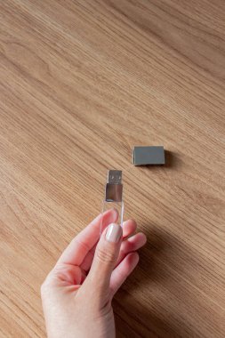 Tahta bir arka planda USB belleği tutan el.