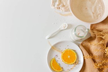 Beyaz arka planda banyo tuzu ve portakal dilimleriyle bej kaplıca kompozisyonu. Düz yerde, üst tarafta. Kadın güzellik tedavi rutin konsepti.