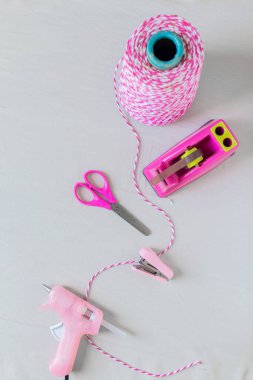 Eser gereksinimleri. Pembe tel, makas, zımba, koli bandı tutacağı ve beyaz arka planda sıcak tutkal tabancası. Kendin yap konsept.. 